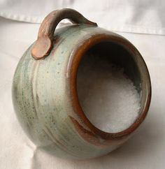 a green and brown vase sitting on top of a white sheet