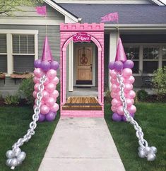 a pink and silver balloon arch in front of a house with balloons attached to it