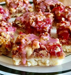 a white plate topped with pieces of cake covered in toppings and drizzled with pink icing