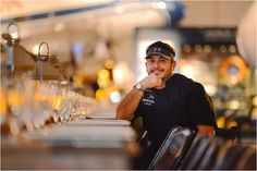 a man sitting at a table in front of wine glasses and looking to the side