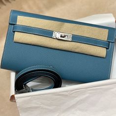 a blue purse sitting on top of a white box next to a black and gold belt