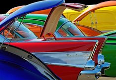 many different colored cars parked side by side in a row with the hood up open