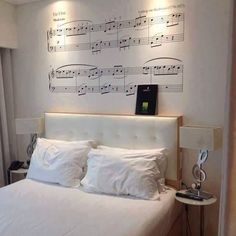 a bed with white sheets and sheet music on the wall