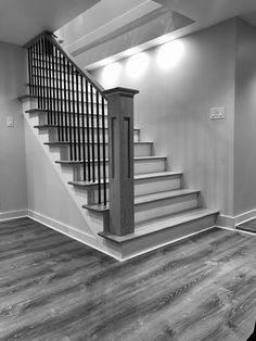 a black and white photo of a stair case in a room with hard wood flooring