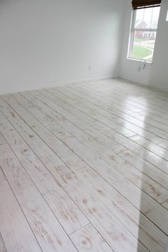 an empty room with white walls and wood floors