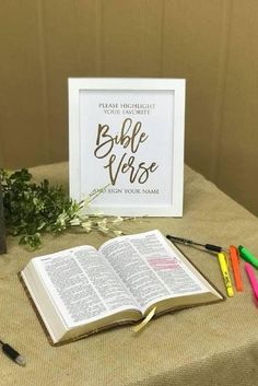 an open bible sitting on top of a table next to some markers and pencils