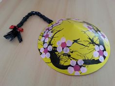 a yellow hat with pink flowers on it sitting on a table next to a string