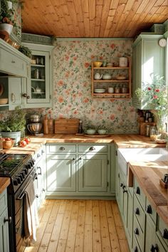 a kitchen with green cabinets and floral wallpaper on the walls, along with wooden flooring