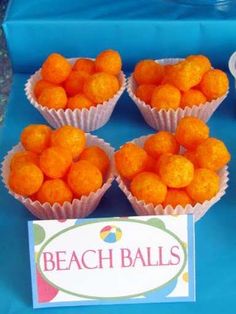 small orange balls are sitting on a blue tablecloth next to a sign that says beach balls