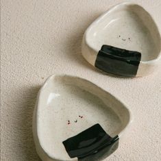 two white bowls with black handles are on the floor