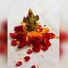 a small statue sitting on top of a white table covered in red and yellow flowers