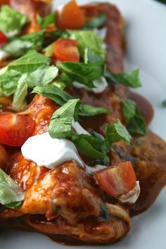 a white plate topped with meat covered in sauce and veggies on top of it