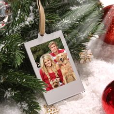 an ornament hanging from a christmas tree with a couple and their dog