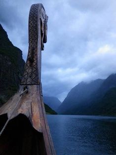 an old wooden boat in the water with mountains in the background