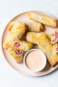 several pastries on a plate with dipping sauce