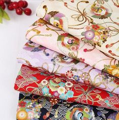 six different colored fabrics are stacked on top of each other, with red berries in the background