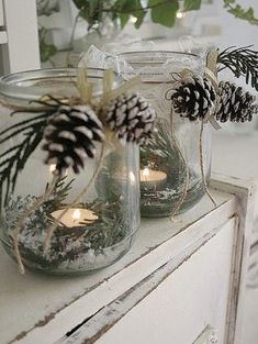 two mason jars filled with pine cones and candles