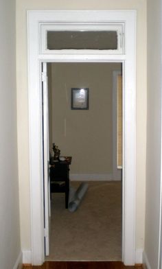 an open door leading to a living room with hard wood floors and white trim on the walls