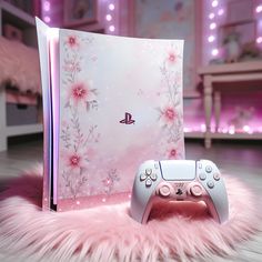 a video game console sitting on top of a fluffy pink rug next to a book