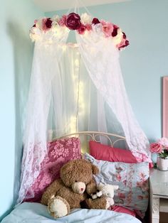 a teddy bear sitting on top of a bed next to a pink flower covered canopy