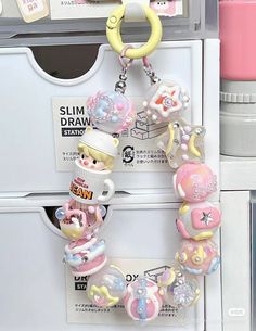 a close up of a key chain with charms on it's sides and an object in the background