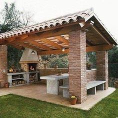 an outdoor kitchen is shown in the backyard with a grill and picnic table under it