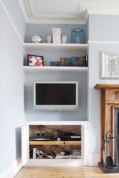 a living room with a fireplace, television and entertainment center in it's corner