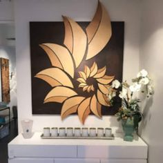 a painting on the wall above a dresser with vases and flowers in front of it