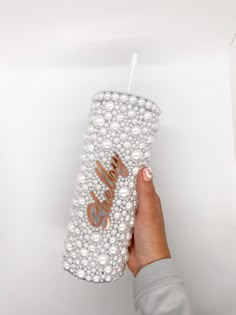 a hand holding a cup with pearls on it and the word smile written on it