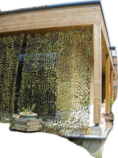 a house covered in green plants next to a wooden structure with windows on the side