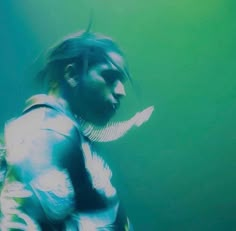 a man with long hair wearing armor and holding a knife in his hand while standing under water