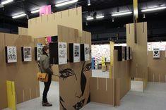 a woman is standing in front of some cardboard walls with pictures on them and holding a purse