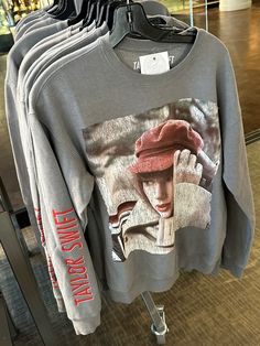 an image of a woman wearing a red hat on a gray sweatshirt hanging in a store