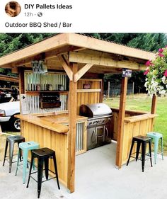 an outdoor bbq shed with stools next to it