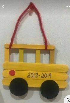 a yellow school bus ornament hanging on a wall with a red string attached to it