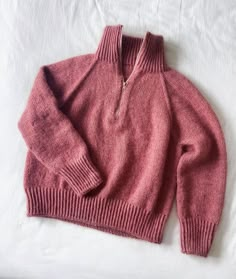 a pink sweater laying on top of a white sheet