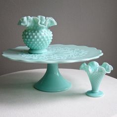 a cake plate with two vases on it and one is sitting on the table