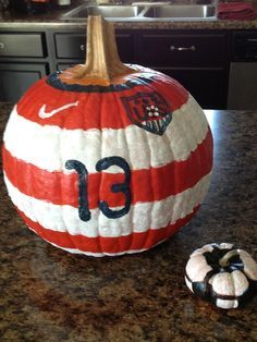 a large red and white striped pumpkin sitting on top of a kitchen counter next to a smaller one