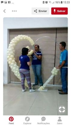 two men and a woman standing in front of a wall with balloons attached to it