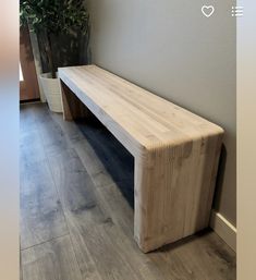 a wooden bench sitting on top of a hard wood floor next to a potted plant