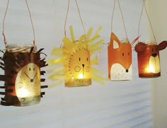 four paper lanterns with animals hanging from the ceiling and one has a light on it