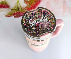 there is a pink cup with sprinkles on it and the word serenity