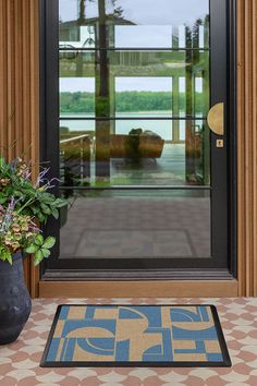 a black vase with flowers sitting on top of a table next to a glass door