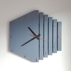 a blue clock with orange hands on a white wall in the shape of hexagonal blocks