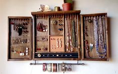 an old wooden jewelry box with many necklaces and bracelets hanging from it's sides