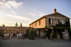 an outdoor dining area with tables and chairs in front of a stone building at sunset