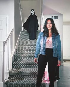 a woman standing in front of some stairs with a ghost on the wall behind her