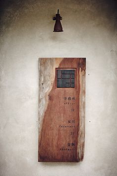 a wooden sign hanging on the side of a wall next to a bell and light