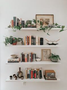 three white shelves filled with books and plants