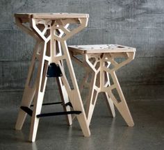 two wooden stools sitting next to each other in front of a cement wall and floor